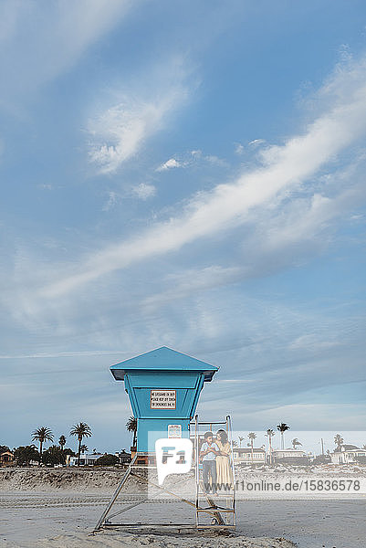 Landschaft von Mutter und Sohn  die auf einem Rettungsschwimmerturm am Strand sitzen