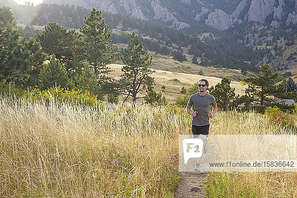 Man runs through tall grass on Bear Canyon Trail in Boulder  Colorado