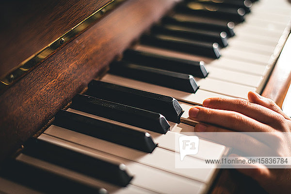 Nahaufnahme der Finger der Hand eines Kindes  die auf Klaviertasten ruhen.