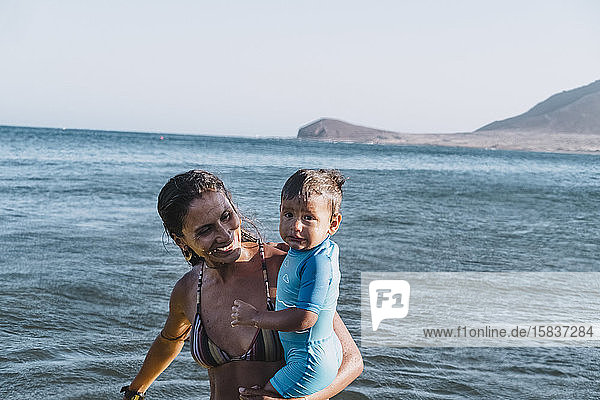 Eine Smiley-Mutter hält ihren Sohn am Strand
