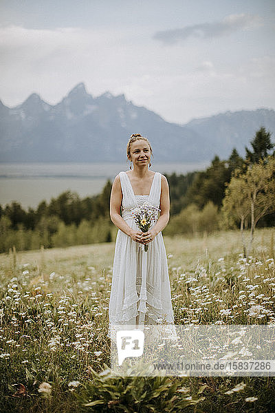 Braut im Wildblumenfeld in Wyoming hält Blumenstrauß.
