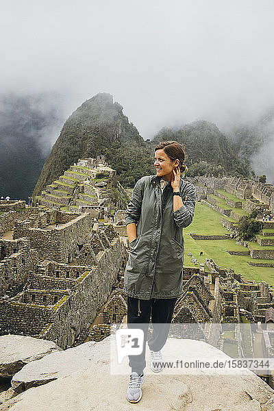 Eine junge Frau steht in der Nähe der Ruinen von Machu Picchu  Peru