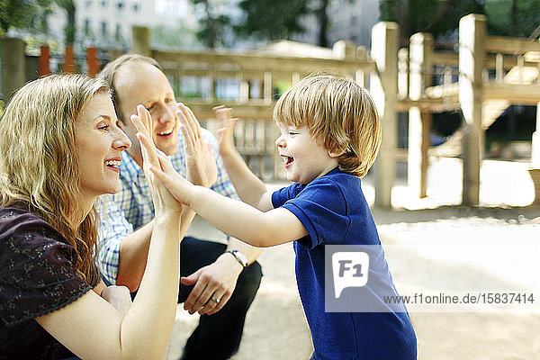 Son giving parents high fives at playground