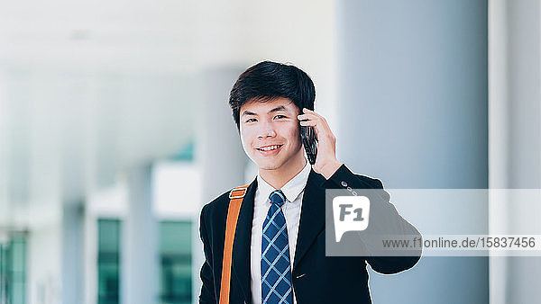 Young businessman in black suit speaking over mobile with partne