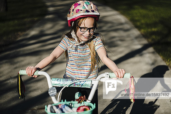 Little Girl Rides Bike Wearing Helmet and Glasses
