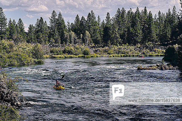 Frau paddelt mit ihrem Ruderfloß den Deschutes River in Oregon hinunter.