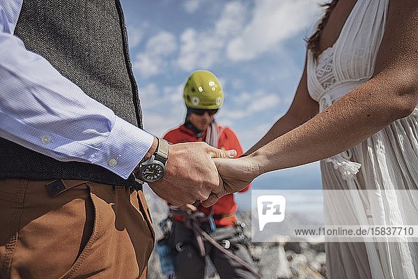 close up of couple holding hands while getting married on a mountain