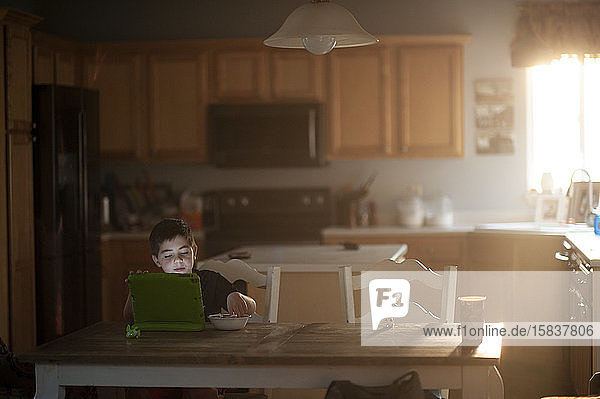 Junge Junge frühstückt  während er in der Küche auf sein Tablett schaut