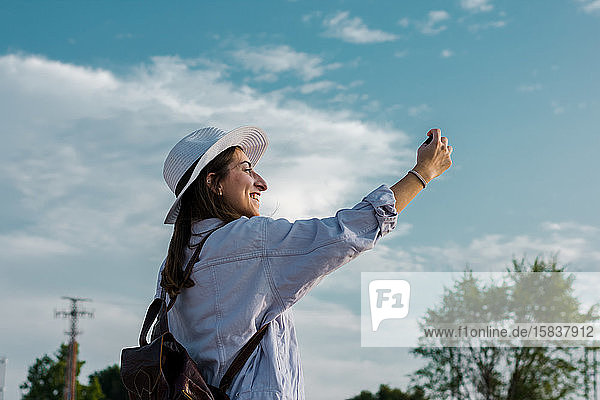 Junge Frau nimmt mit ihrem Smartphone ein Selbstporträt auf. Reisen  Lebensstil