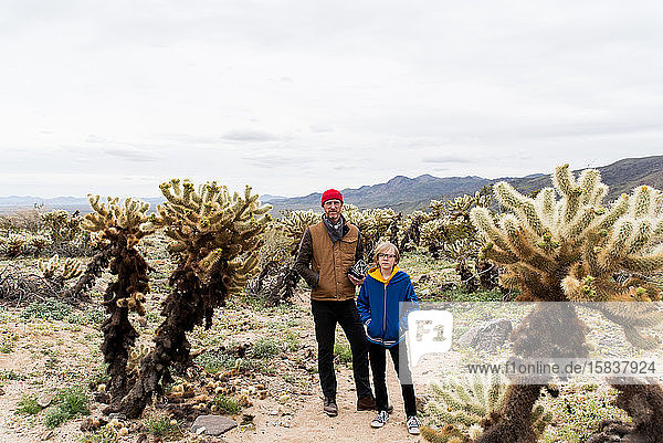 Vater und Sohn im Cholla-Kakteenfeld  das sich bis zu weit entfernten Hügeln erstreckt