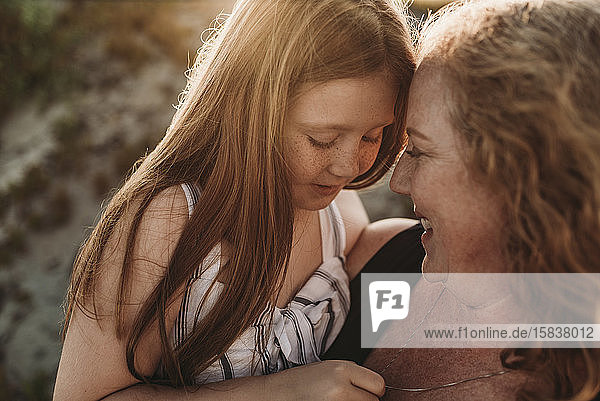 Side view of mother and redheaded elementary age daughter at sunset