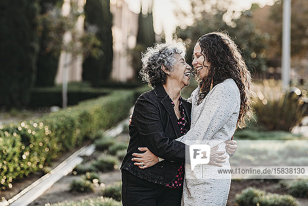 Aktive ältere Großmutter und erwachsene Tochter umarmen sich draußen