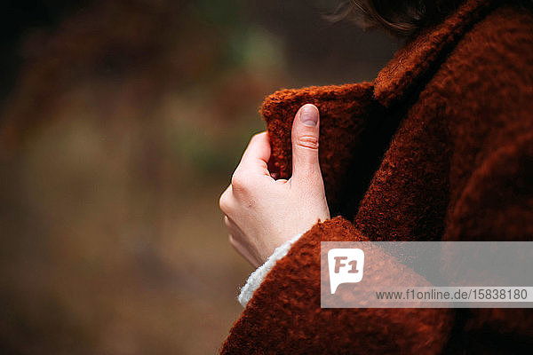 Unrecognizable female hands in bright brown coat in autumn