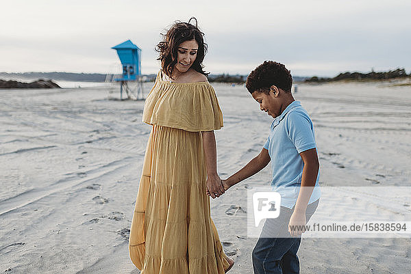 Nahaufnahme einer jungen Mutter und eines schulpflichtigen Sohnes beim Strandspaziergang