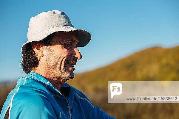 A profile shot of an older man. Autumn mountains background