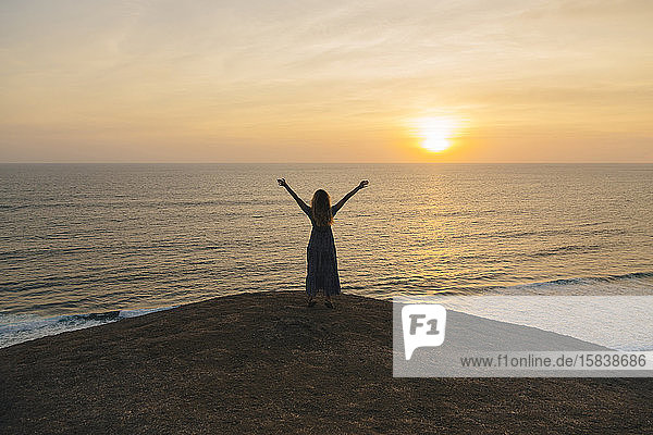 Young woman standing at the sea at sunset