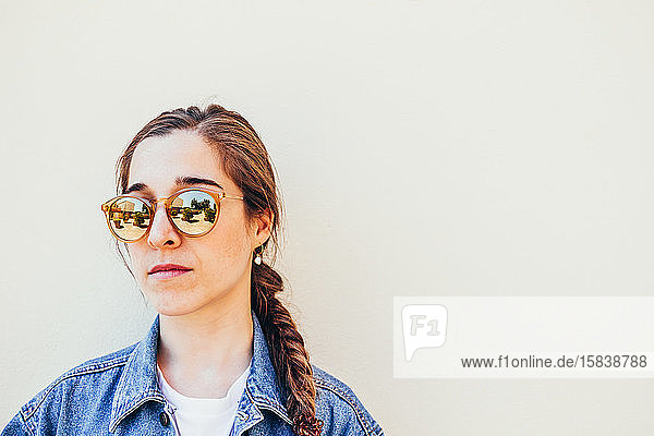 Nahaufnahme einer attraktiven jungen Frau mit Sonnenbrille auf pastellfarbenem Hintergrund