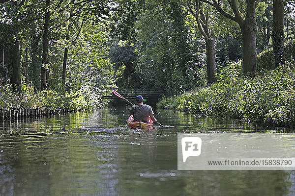 Eine Person  die auf einem Kanal auf dem Land in Utrecht Kajak fährt