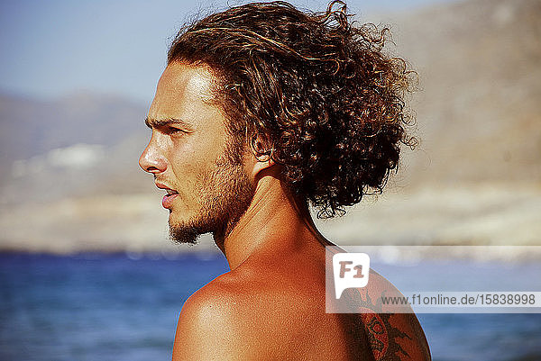 Hübscher Mann an einem sonnigen Tag am Strand auf der Insel Amorgos