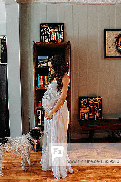 Schwangere Frau weißes Kleid und Bücherregal