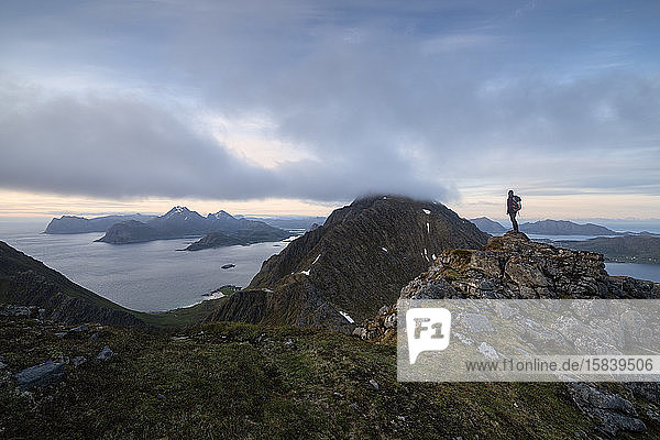 Female hiker overlooks moutain landscape from Middagstind  FlakstadÃ¸y  Lofoten Islands  Norway