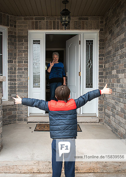 Social distance visit between young boy and his grandmother at home.