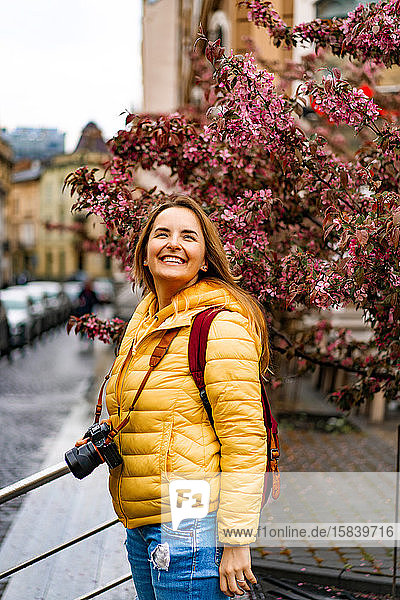 Junge Touristin mit Kamera lächelt in der europäischen Altstadt