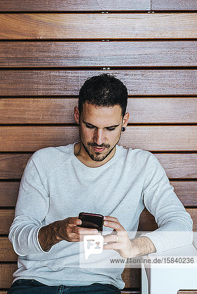 Portrait of young man sitting in a coffee shop using cell phone