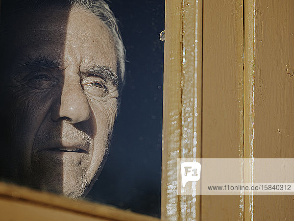 Ein alter Mann schaut durch das Fenster.