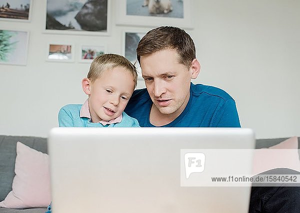 Vater und bald lächelnd gemeinsam zu Hause auf einen Laptop schauen