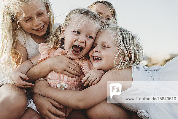 Nahaufnahme eines lachenden Kleinkindes umgeben von jungen Schwestern