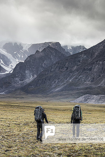 rear view of two backpackers heading into the mountains.