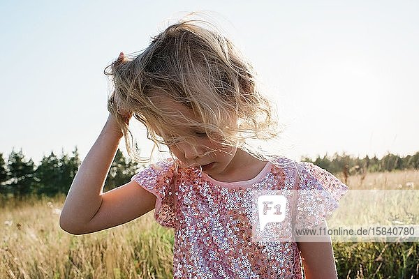 Porträt eines jungen Mädchens  dessen Haare bei Sonnenuntergang im Wind wehen