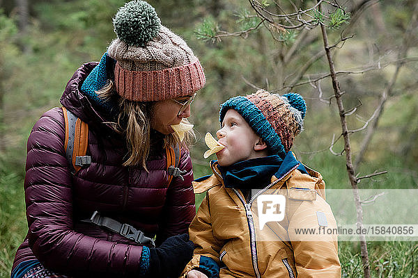 mom and her son making silly faces whilst eating & hiking in winter