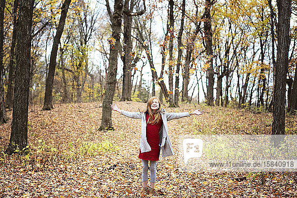 Junges rothaariges Mädchen spielt draußen im Herbstlaub