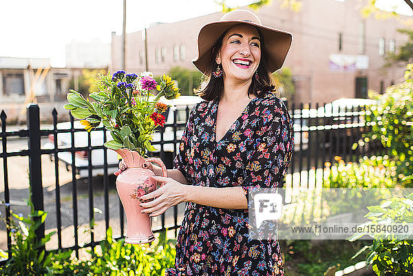 glückliche Frau lächelt im Stadtgarten mit frischen Blumen