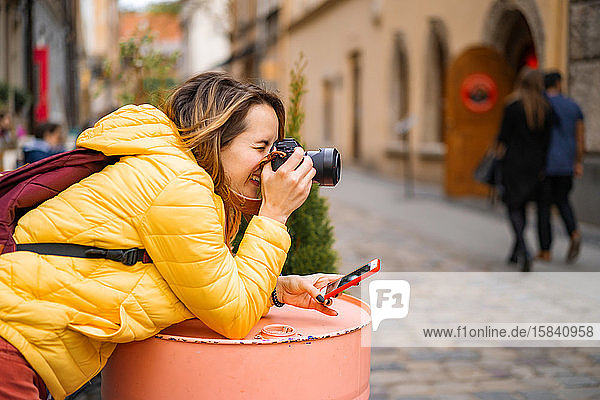Junge Touristin mit einem Kamera-Smartphone  die im Freien fotografiert