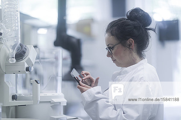 junge Wissenschaftlerin mit Tablette in einem Labor