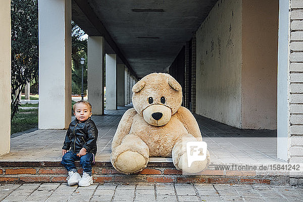 Ein kleiner Junge spielt mit einem riesigen Teddybären.