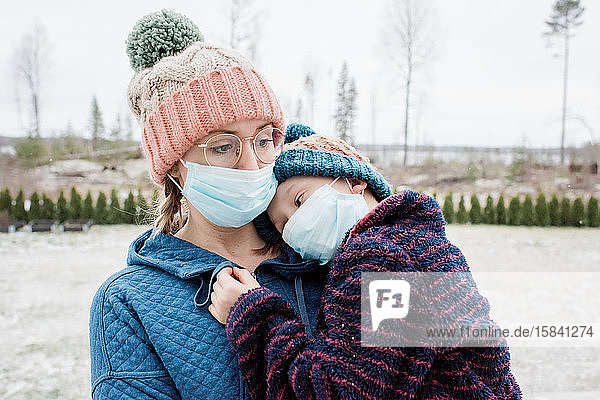 mother carrying son with face masks on as protection from virus & flu