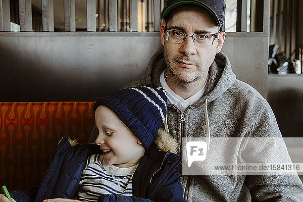 Vater und Sohn malen in Restaurantkabine und warten auf Essen