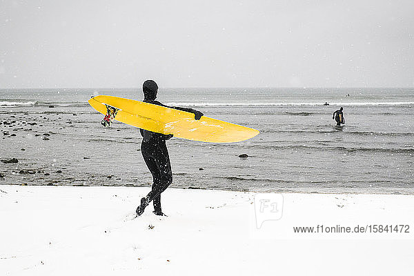 Frau macht sich an einem verschneiten Tag zum Surfen bereit