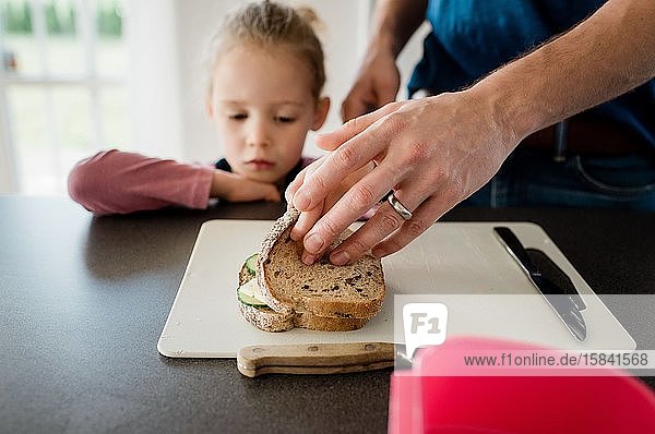 der Vater macht seinen Kindern Lunchpakete für die Schule  während die Tochter schaut