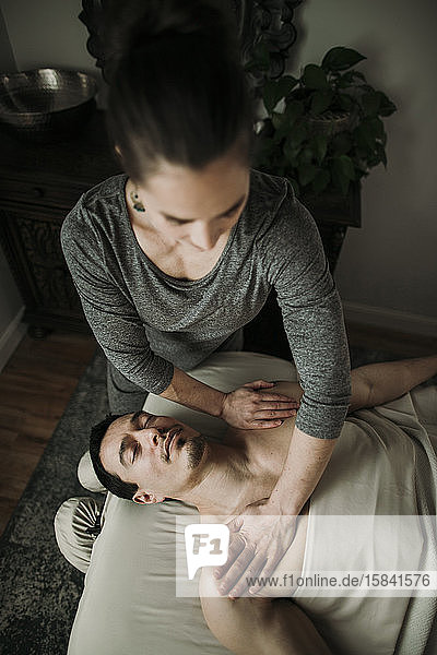 Männlicher Massage-Klient erhält Druck auf seine Schultern vom Therapeuten