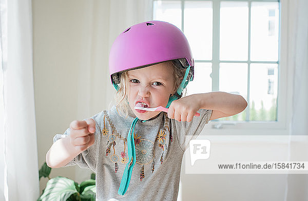 junges Mädchen  das sich zu Hause mit einem Helm die Zähne putzt