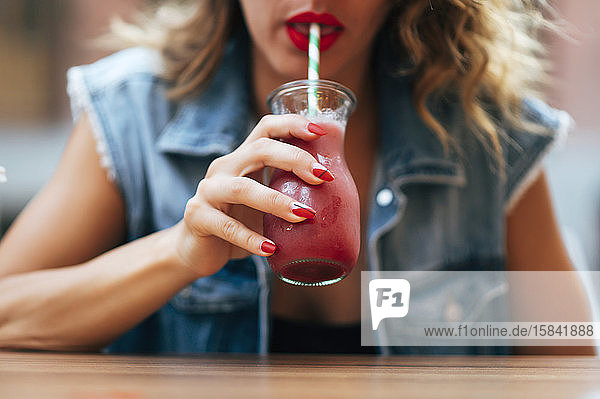 Hübsche Frau mit roten Lippen trinkt ein Cocktail-Soda