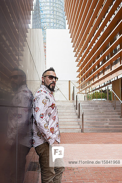 Side view of a bearded male leaning on a office building wall