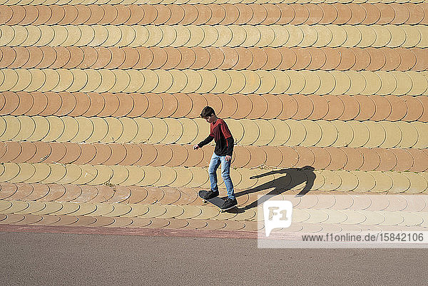 Junge Junge skatet auf Rampe in einem Stadtpark an einem sonnigen Tag