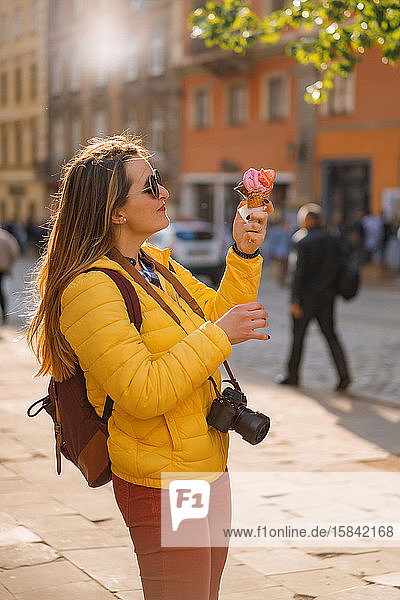 Junge Touristin isst Eis an einem sonnigen Tag in einer eupöischen Stadt