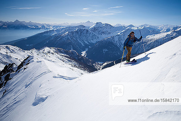 Mann in blauer Jacke Skitouren auf Bergrücken